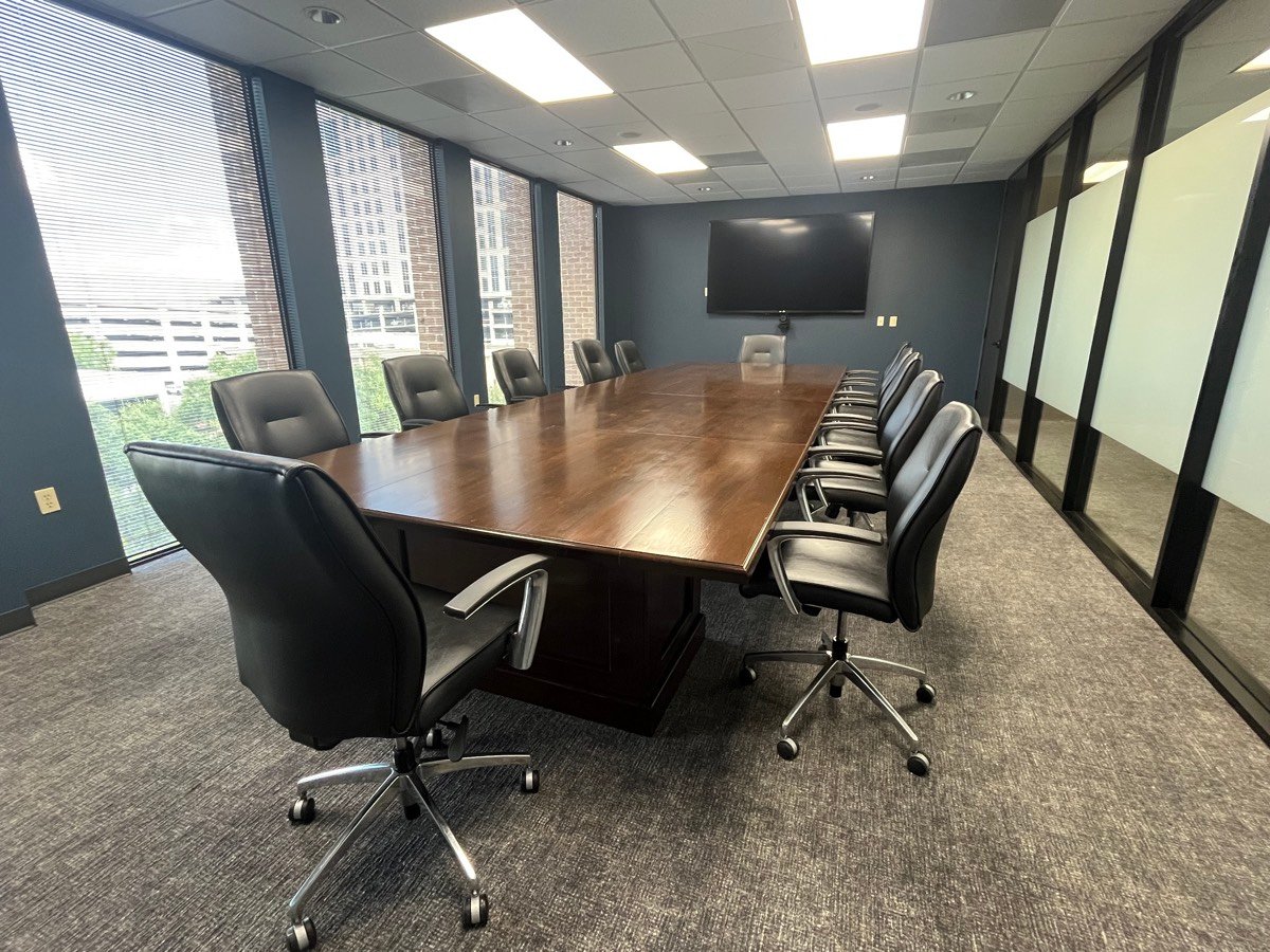 Shared conference room with a twelve-seat table, wall-mounted display, and skyline views